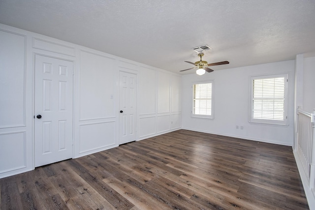 empty room with ceiling fan, dark wood-type flooring, and a textured ceiling