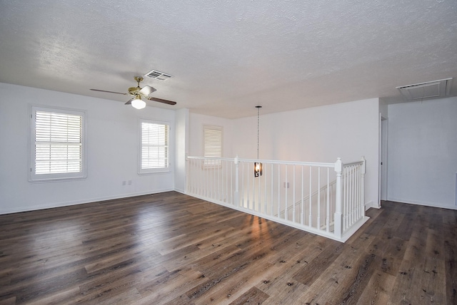 unfurnished room with a textured ceiling, ceiling fan, and dark wood-type flooring