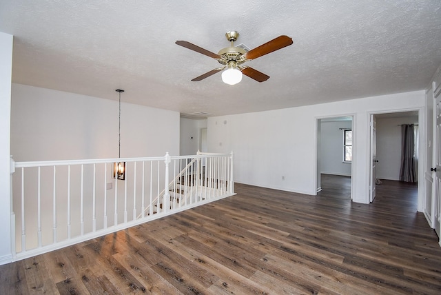 unfurnished room with a textured ceiling, dark hardwood / wood-style floors, and ceiling fan