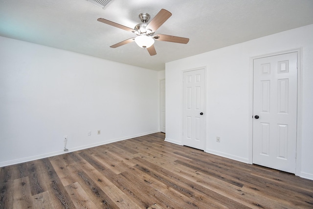 unfurnished bedroom with two closets, dark hardwood / wood-style floors, and ceiling fan