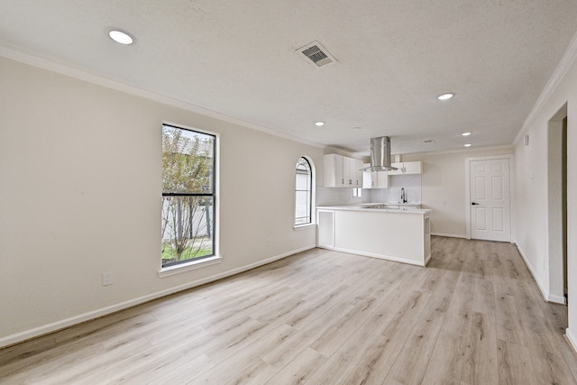 kitchen featuring kitchen peninsula, island exhaust hood, crown molding, light hardwood / wood-style flooring, and white cabinets