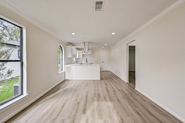 unfurnished living room featuring plenty of natural light, light hardwood / wood-style floors, and ornamental molding