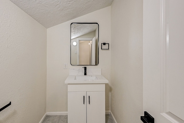 bathroom with vanity, lofted ceiling, and a textured ceiling