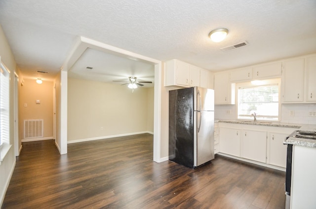 kitchen featuring backsplash, dark wood-type flooring, white cabinets, sink, and stainless steel refrigerator