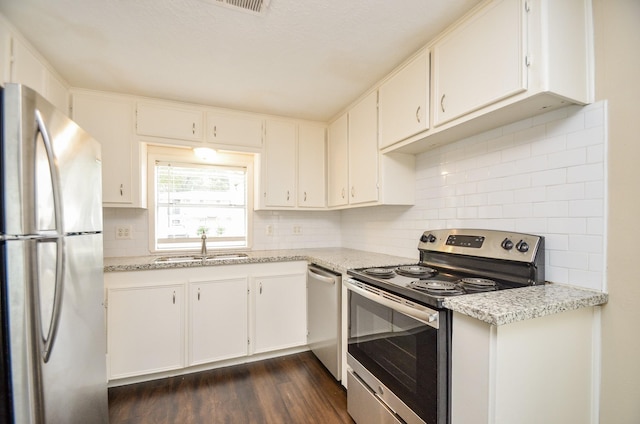 kitchen with light stone countertops, white cabinetry, stainless steel appliances, and dark wood-type flooring