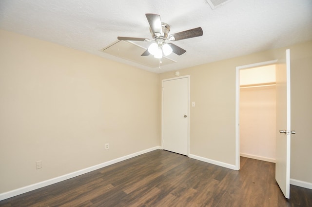 unfurnished bedroom featuring a closet, dark hardwood / wood-style floors, a spacious closet, and ceiling fan