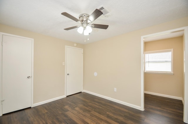 unfurnished bedroom featuring a textured ceiling, ceiling fan, and dark wood-type flooring