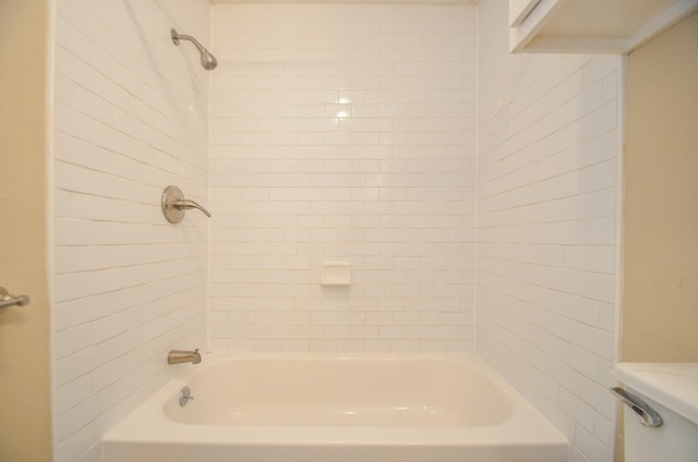 bathroom featuring tiled shower / bath combo and toilet