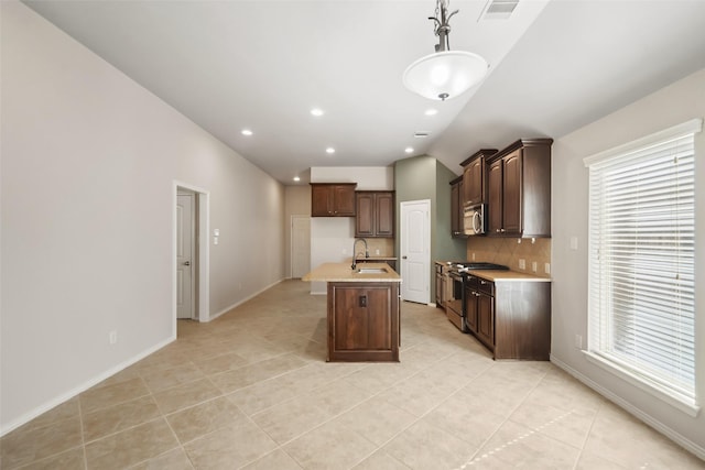 kitchen featuring hanging light fixtures, sink, vaulted ceiling, an island with sink, and appliances with stainless steel finishes