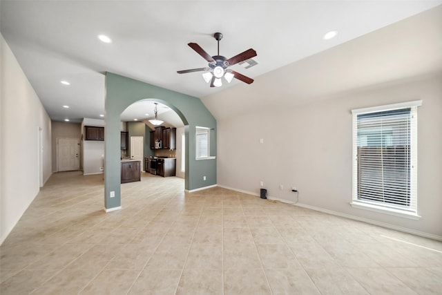 unfurnished living room with ceiling fan, light tile patterned flooring, and vaulted ceiling