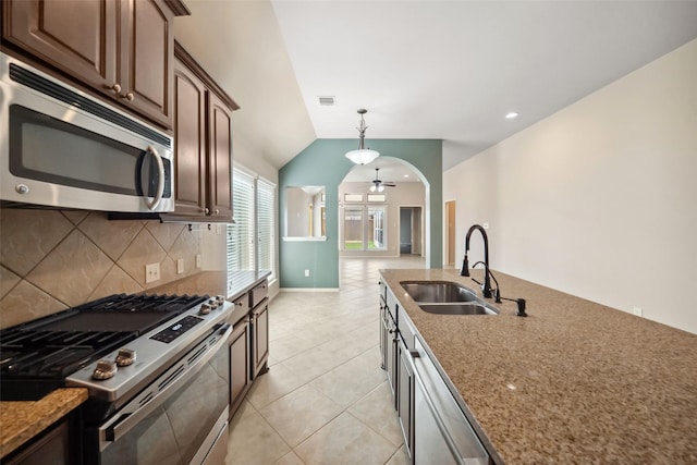 kitchen featuring decorative backsplash, light stone counters, stainless steel appliances, sink, and lofted ceiling