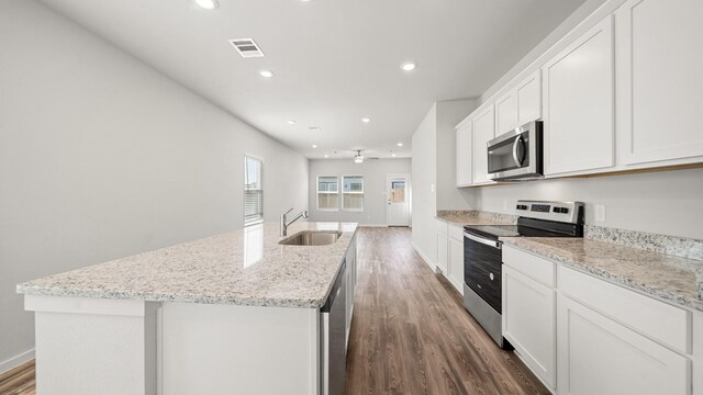 kitchen with white cabinets, sink, stainless steel appliances, and an island with sink