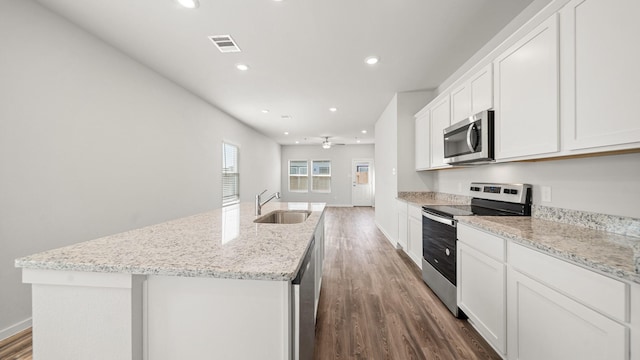 kitchen with stainless steel appliances, white cabinetry, sink, and a kitchen island with sink