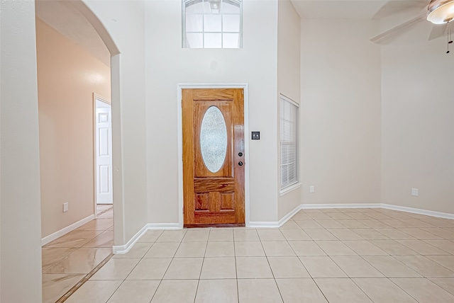 tiled foyer with ceiling fan and a high ceiling