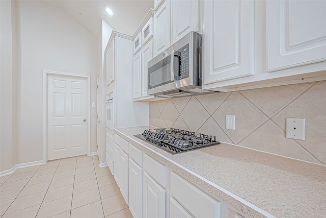 kitchen featuring gas cooktop, decorative backsplash, white cabinetry, and light tile patterned flooring