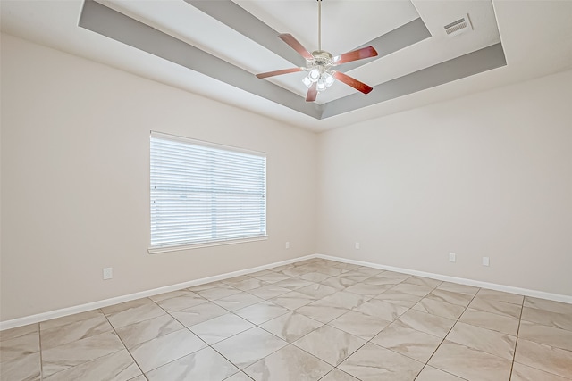 spare room featuring a tray ceiling and ceiling fan