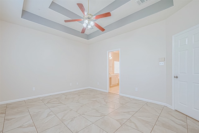 spare room with a tray ceiling and ceiling fan