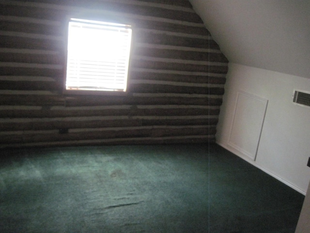 additional living space featuring vaulted ceiling and dark colored carpet