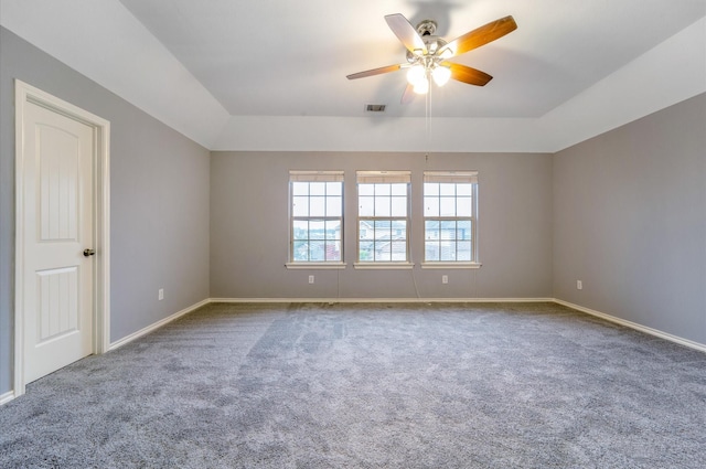 empty room featuring carpet, a raised ceiling, and ceiling fan