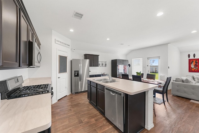 kitchen featuring sink, vaulted ceiling, a center island with sink, dark hardwood / wood-style flooring, and appliances with stainless steel finishes