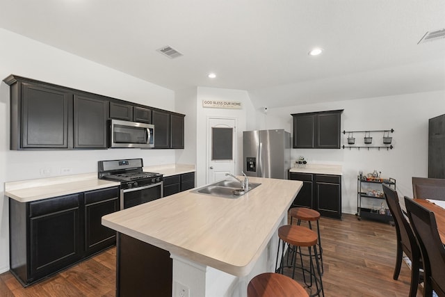 kitchen featuring a center island with sink, stainless steel appliances, a breakfast bar, dark wood-type flooring, and sink