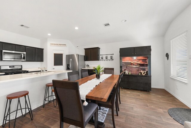 dining space featuring sink, vaulted ceiling, and dark hardwood / wood-style floors