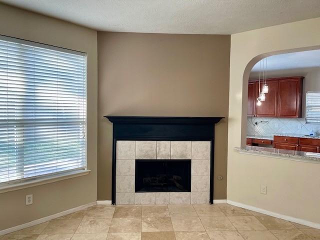 unfurnished living room with a tile fireplace, light tile patterned floors, and plenty of natural light