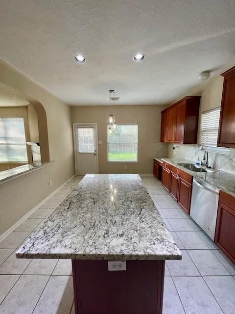 kitchen with hanging light fixtures, dishwasher, a healthy amount of sunlight, and sink