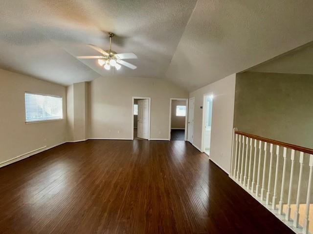 unfurnished room with ceiling fan, dark hardwood / wood-style flooring, lofted ceiling, and a textured ceiling