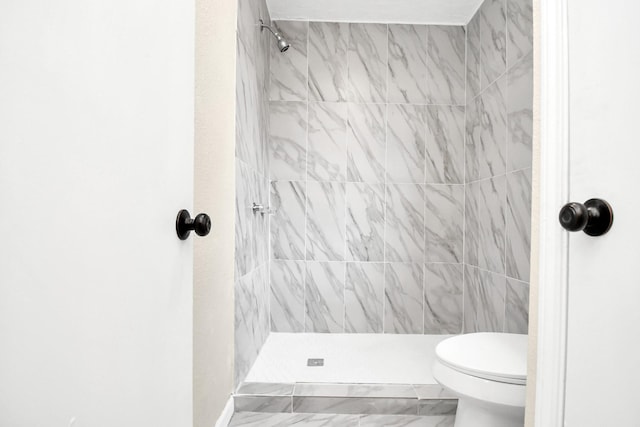 bathroom featuring tiled shower and toilet