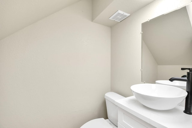 bathroom featuring vanity, lofted ceiling, and toilet