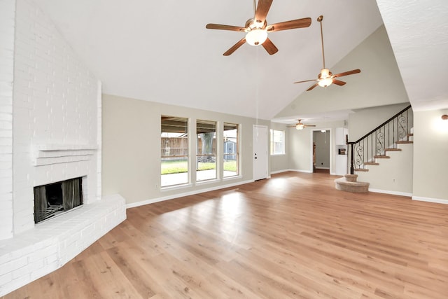 unfurnished living room featuring a fireplace, high vaulted ceiling, light hardwood / wood-style flooring, and ceiling fan