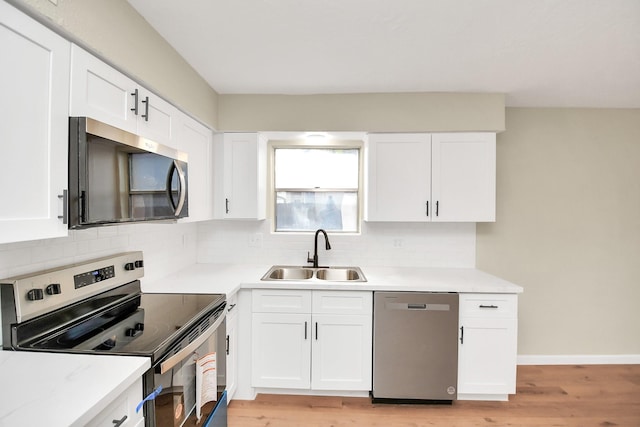 kitchen featuring sink, light hardwood / wood-style flooring, appliances with stainless steel finishes, white cabinetry, and decorative backsplash