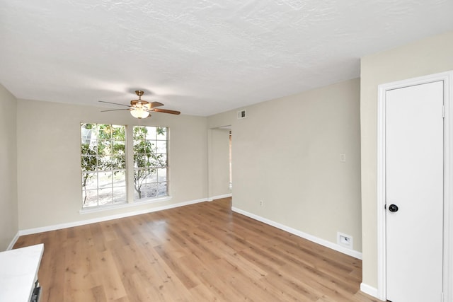 empty room with ceiling fan, light hardwood / wood-style flooring, and a textured ceiling