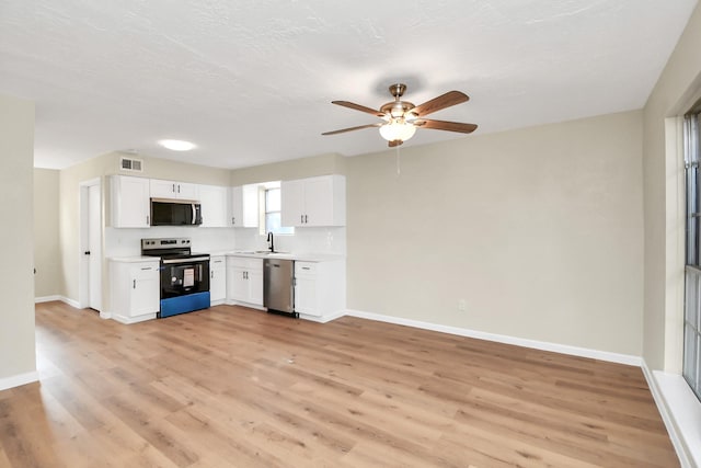 kitchen featuring appliances with stainless steel finishes, white cabinetry, sink, ceiling fan, and light wood-type flooring