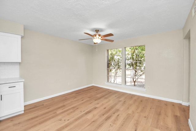 unfurnished room featuring a textured ceiling, light hardwood / wood-style flooring, and ceiling fan