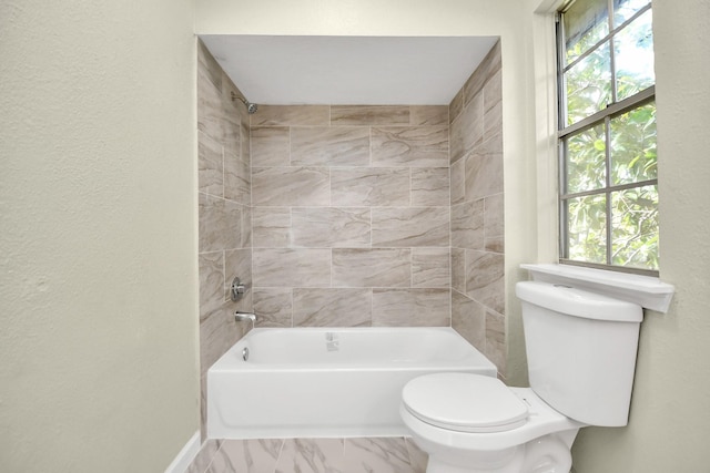 bathroom with tiled shower / bath, toilet, and a wealth of natural light