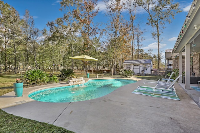 view of pool featuring pool water feature, a patio area, and an outdoor structure