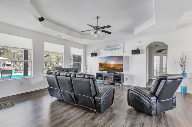 living room featuring ceiling fan, french doors, dark wood-type flooring, and a tray ceiling