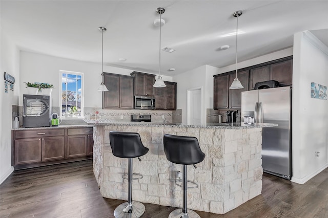 kitchen featuring a center island with sink, decorative light fixtures, dark hardwood / wood-style flooring, and appliances with stainless steel finishes