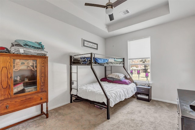 bedroom with a tray ceiling, ceiling fan, and carpet