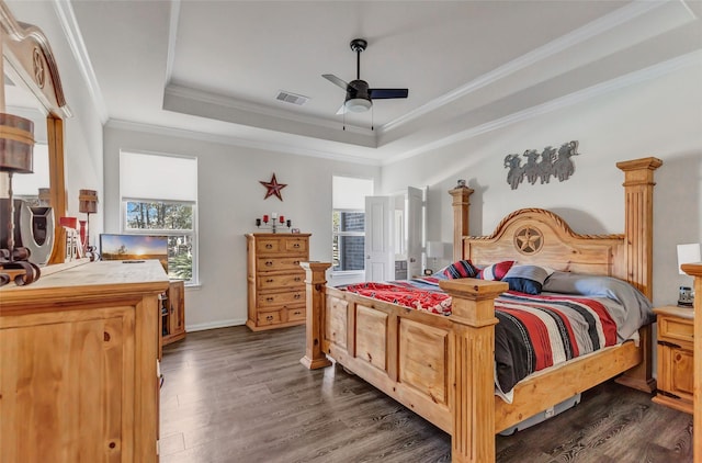 bedroom with ornamental molding, a raised ceiling, ceiling fan, and dark wood-type flooring