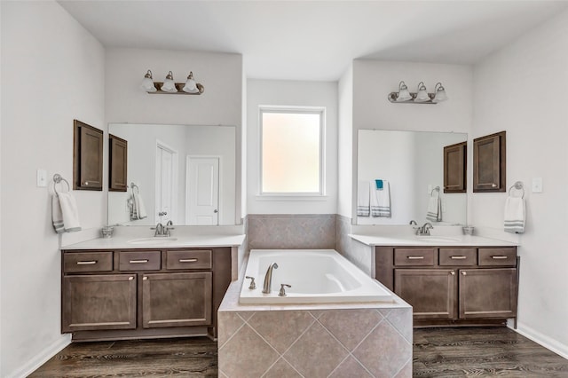 bathroom with tiled tub, vanity, and wood-type flooring