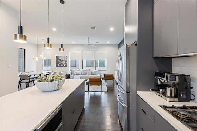 kitchen featuring gray cabinetry, dark hardwood / wood-style flooring, decorative light fixtures, and appliances with stainless steel finishes