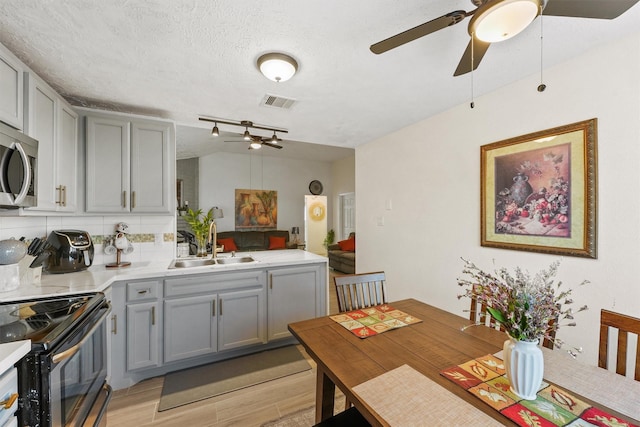 kitchen featuring tasteful backsplash, a textured ceiling, black range with electric cooktop, sink, and light hardwood / wood-style flooring