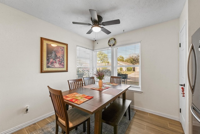 dining space featuring ceiling fan, light wood-type flooring, and a textured ceiling