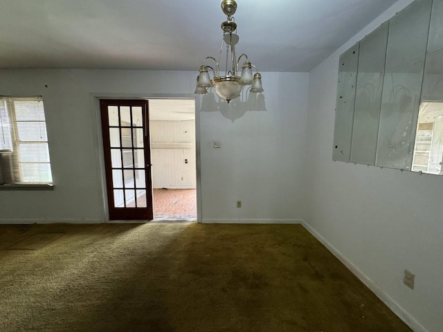 carpeted spare room with a chandelier