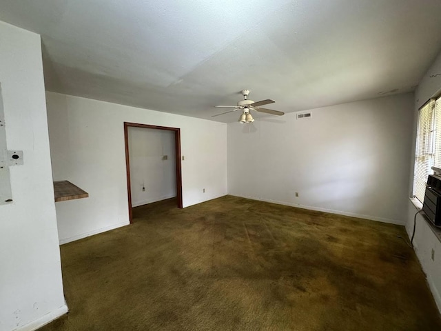 empty room with dark colored carpet and ceiling fan