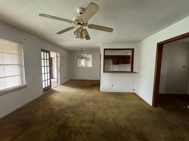 unfurnished living room featuring dark colored carpet and ceiling fan with notable chandelier