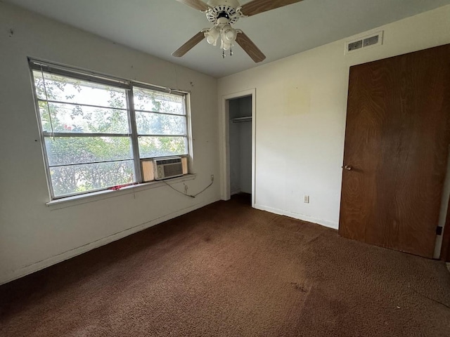 unfurnished bedroom with cooling unit, ceiling fan, dark carpet, and a closet